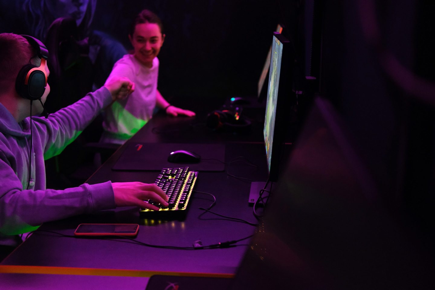 Two gamer teenagers work on computers.