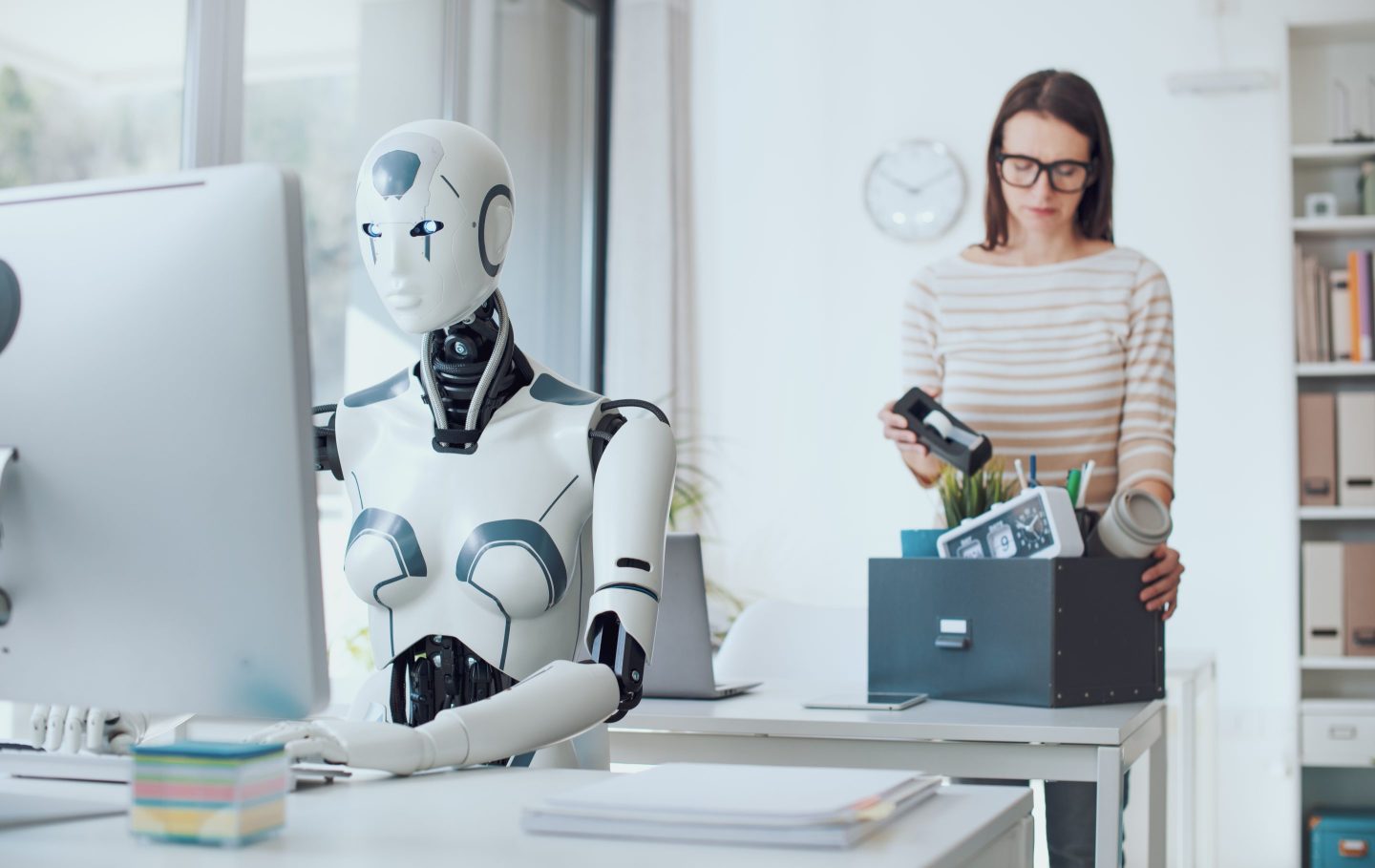 Woman packing her stuff as an AI worker types on a computer