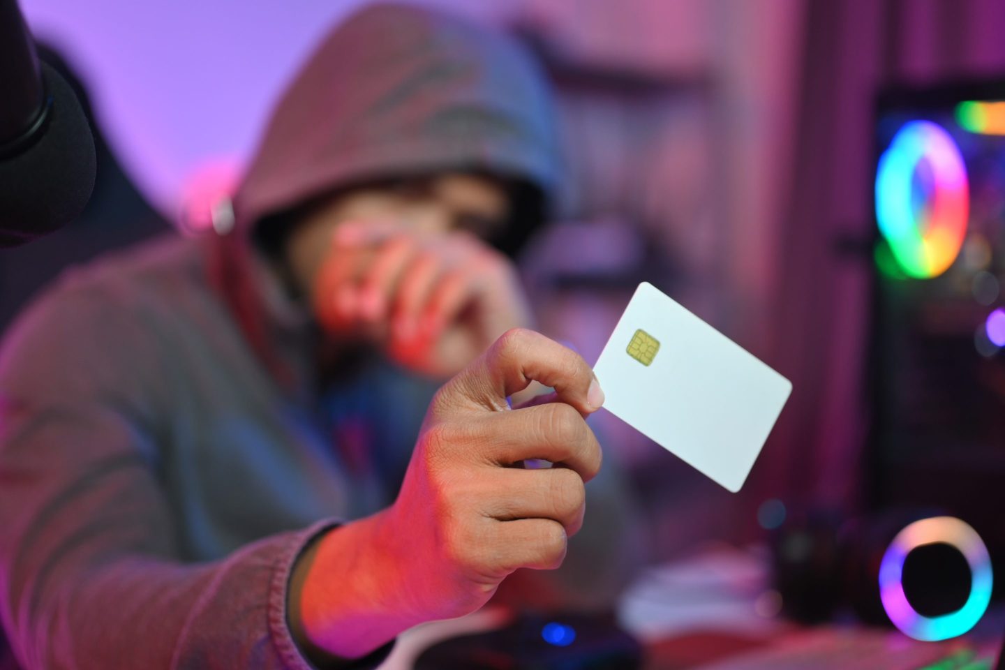 A person in a hoodie holding a credit card.