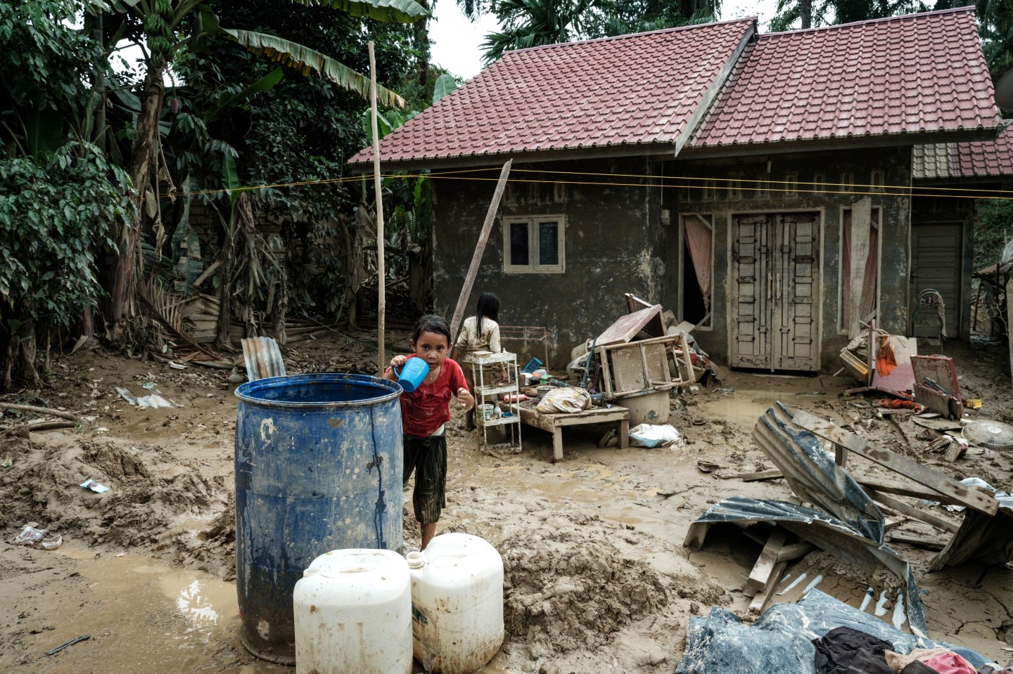 A girl draws water from a storage tank in Babo, Aceh Tamiang, Northern Sumatra, on December 15, 2025, following a flash flood. Indonesia will revoke more than 20 forestry permits across the country, the forestry minister said on December 15, after deadly floods and landslides devastated parts of the northwestern island of Sumatra. (Photo by Yasuyoshi CHIBA / AFP via Getty Images)