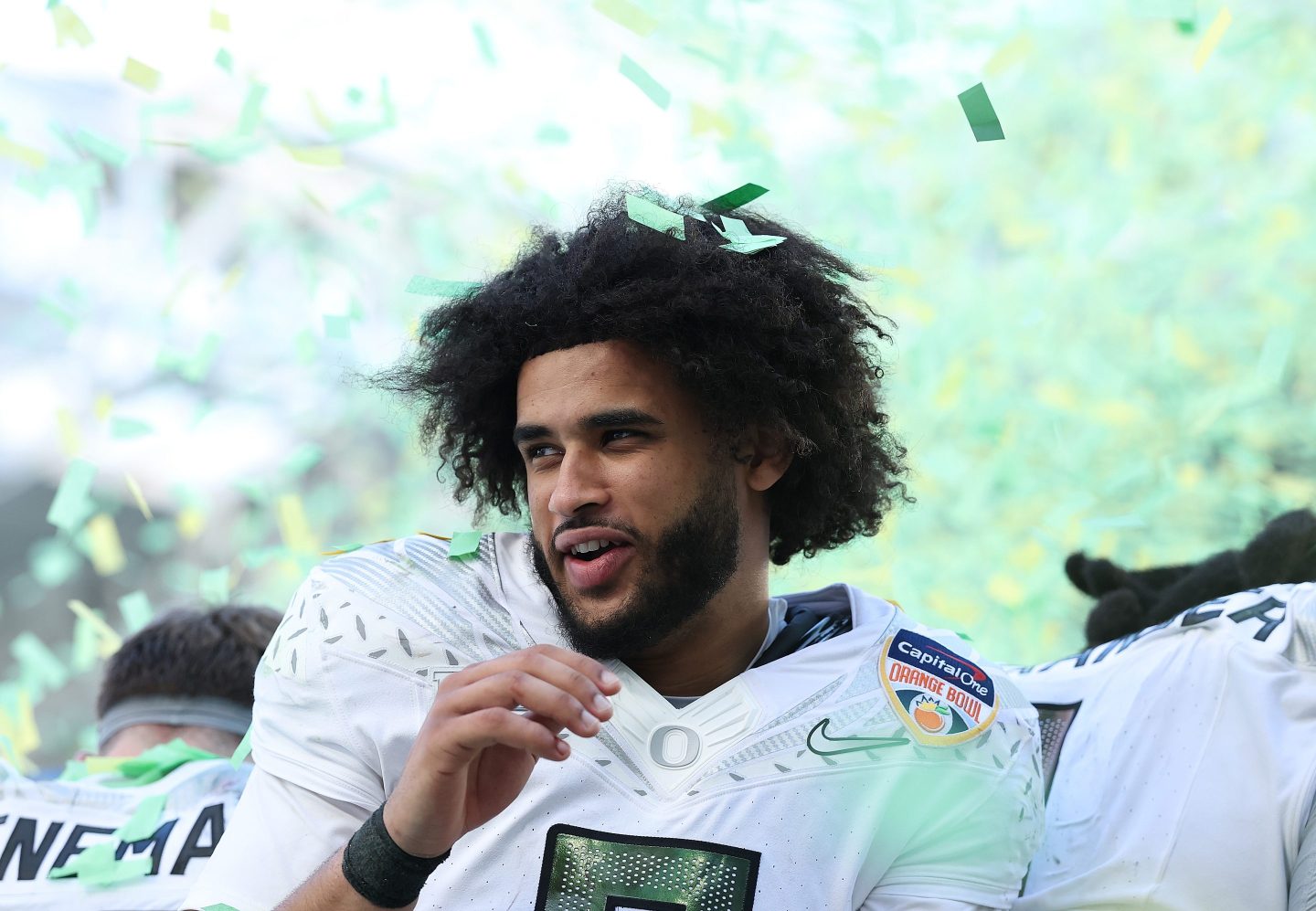 Dante Moore reacts to green and white confetti falling on him.