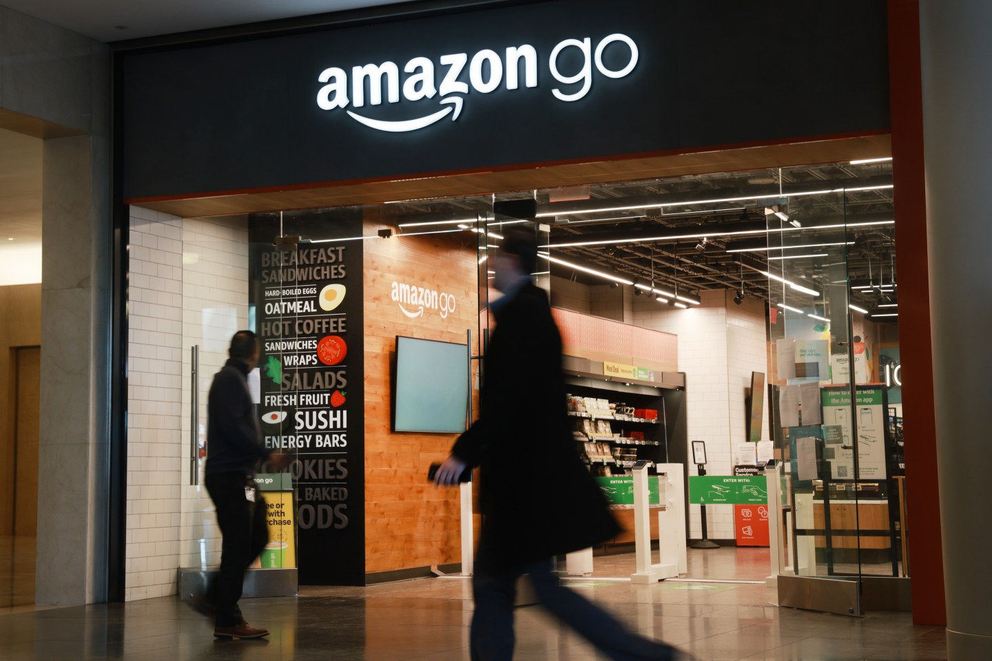 NEW YORK, NEW YORK - JANUARY 28: People walk past an Amazon Go store in a Manhattan mall on January 28, 2026 in New York City. Saying it needs to focus on its AI market, the global company has announced it is laying off 16,000 employees, its second large-scale round of job cuts in recent months. (Photo by Spencer Platt/Getty Images)